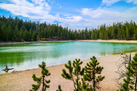 A very small crystal clear lake in the forest of Yellowstone National Park, Wyomingの写真素材