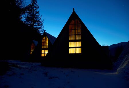 Snow-covered small houses at night in mountains