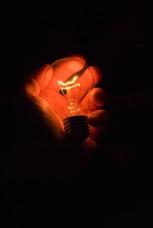 luminous bulb in hand on black backgroundの写真素材
