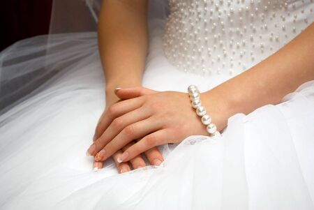 hands of fiancee are together on white dressの写真素材