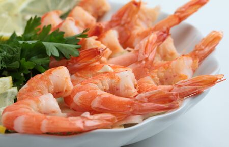 cooked shrimp with fresh herbs and lemon on a plate on a white backgroundの写真素材