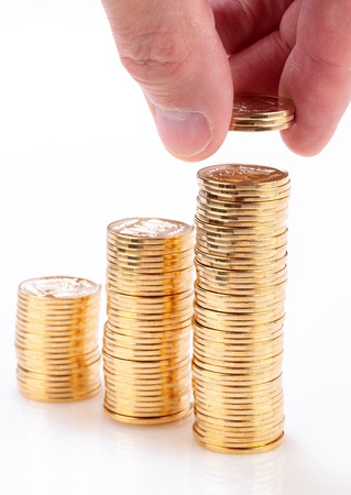 Many gold coins stacked by hand isolated on a white background.の写真素材