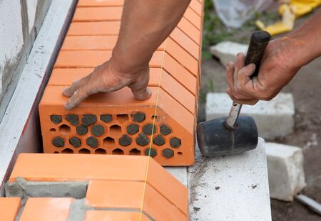 Builder lays Bricks in cement mortar