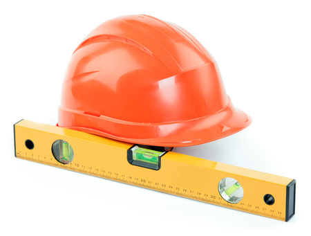 Level and the orange plastic construction Helmet on a white background