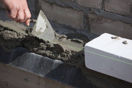 Builder lays Bricks in cement mortarの写真素材