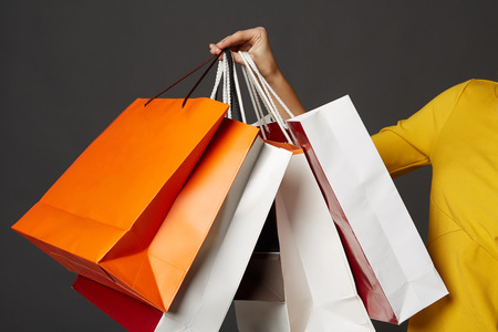 Shopping young woman in the yellow with bags on black の写真素材