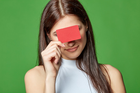 Happy smiling girl in casual clothing, showing blank credit card, on green backgroundの写真素材