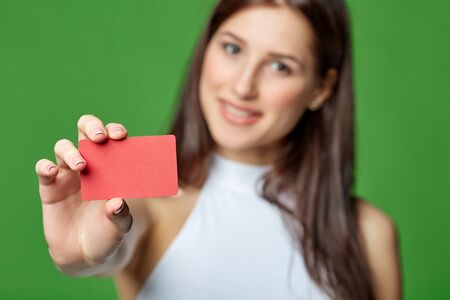 Happy smiling girl in casual clothing, showing blank credit card, on green backgroundの写真素材