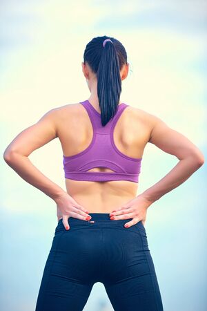 Fitness, healthcare and medicine concept - close up of sporty woman touching her back