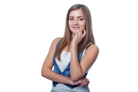 Young stylish slim tanned female standing with hand on chin, isolated on white backgroundの写真素材