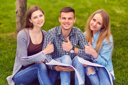 Group of college students exchanging notes outdoorsの写真素材