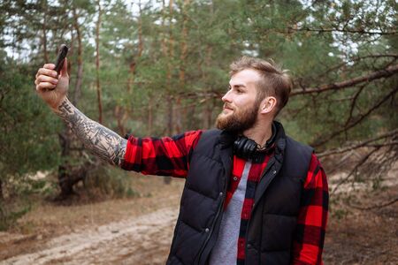 Handsome man making photo on smartphone outdoors
