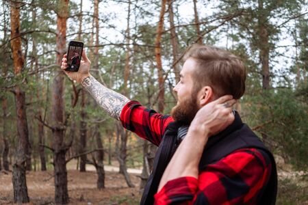 Handsome man making photo on smartphone outdoors.の写真素材