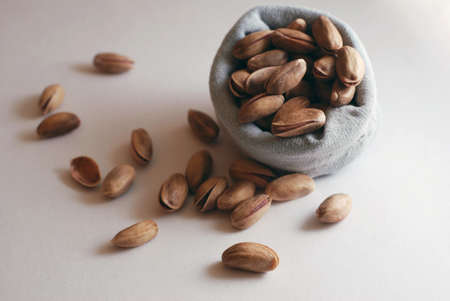 Pistachio nuts falling out of  small bag on white table 