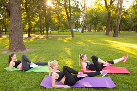 girls doing aerobics exercises together outdoors in a parkの写真素材