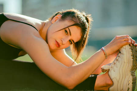 close up of fit young beautiful woman in black sporty leggings working out outdoors in park on summer day, doing Standing Head to Knees posture, Uttanasana pose, full lengthの写真素材