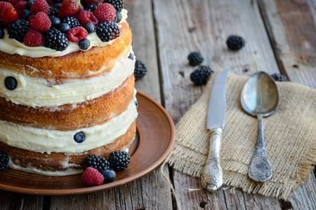 Tasty cake with strawberry, raspberry and blackberry on a wooden table