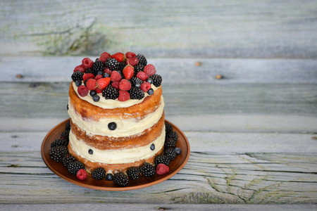 Tasty cake with strawberry, raspberry and blackberry on a wooden table