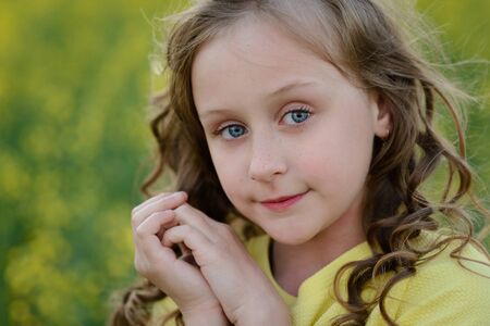 The beautiful girl in a yellow dress on the blossoming fieldの写真素材