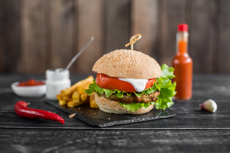 Tasty hamburger with meat and vegetables against a dark background.の写真素材
