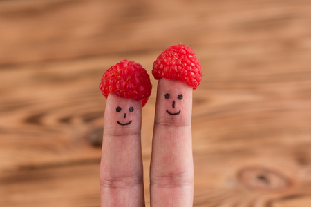 Two smiling faces drawn on fingers in capsules from raspberryの写真素材