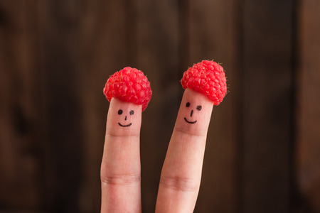 Two smiling faces drawn on fingers in capsules from raspberryの写真素材