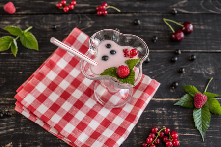 Smoothie from raspberry in a glass on a wooden background with different fruit. It can be used as a backgroundの写真素材