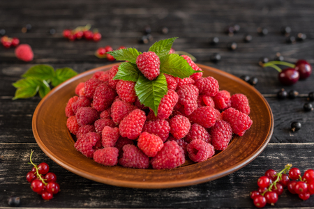 Tasty juicy sweet raspberry on a wooden background. It can be used as a background