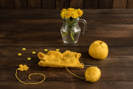 Knitted kids wear yellow color on a dark wooden backgroundの写真素材