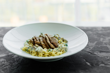 Dish with meat pieces, pasta, greens, sauce from a foie gras and the olive earthの写真素材