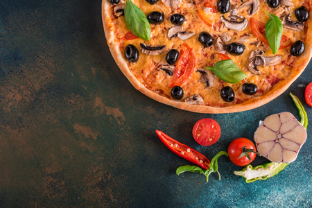 Tasty fresh hot pizza against a dark background. Pizza, food, vegetable, mushroomsの写真素材