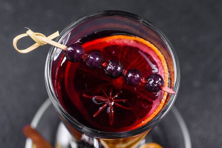 Christmas hot mulled wine with cinnamon cardamom and anise on a dark background. Glass mugs of hot mulled wine with spices and citrus fruitsの写真素材