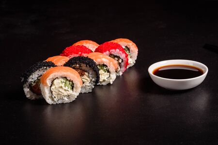 Various kinds of sushi served on a dark background. Roll with salmon, avocado, cucumber. Sushi menu. Japanese food.の写真素材