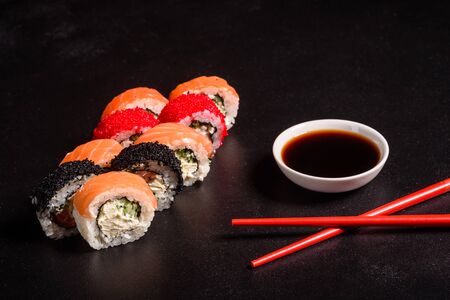 Various kinds of sushi served on a dark background. Roll with salmon, avocado, cucumber. Sushi menu. Japanese food.の写真素材