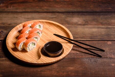 Various kinds of sushi served on a dark background. Roll with salmon, avocado, cucumber. Sushi menu. Japanese food.の写真素材