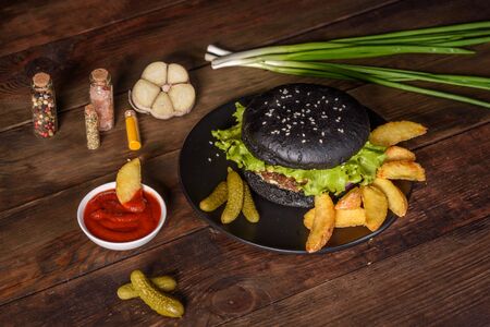 Tasty grilled homemade burger with beef, tomato, cheese, cucumber and lettuce. Delicious grilled burgers. Craft beef burger and french fries on wooden tableの写真素材