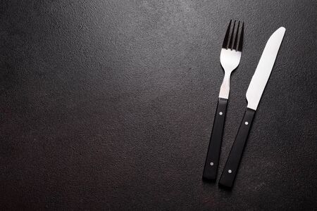Set of tableware ready for the meal with black copy space. Metal knife, fork, spoon and plate on the dark backgroundの写真素材