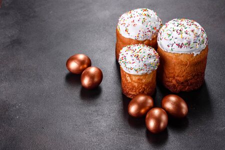Easter eggs gold and bronze and Easter cake on a dark background. Preparation for the holidayの写真素材