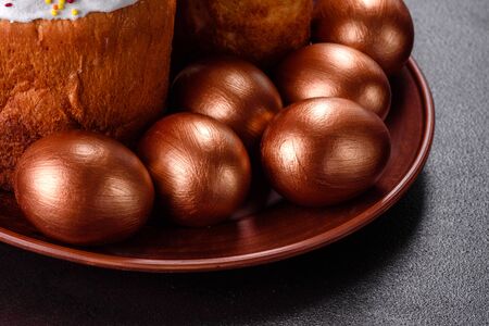 Easter eggs gold and bronze and Easter cake on a dark background. Preparation for the holiday