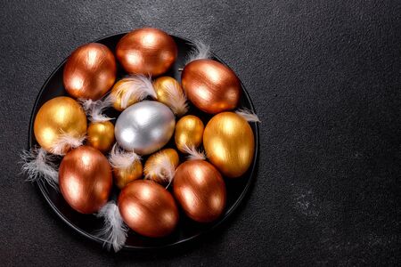Easter eggs gold and bronze and Easter cake on a dark background. Preparation for the holidayの写真素材