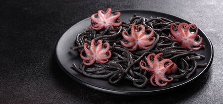 Black seafood pasta with shrimp, octopus and mussels on black background. Mediterranean gourmet...