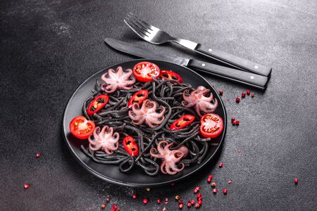 Black seafood pasta with shrimp, octopus and mussels on black background. Mediterranean gourmet food. Black pasta with octopus on a black stone plateの写真素材