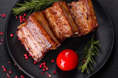 Fried ribs with rosemary, onion, sauce on a concrete background. Dark table. Place for text, copyspaceの写真素材