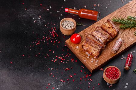 Fried ribs with rosemary, onion, sauce on a concrete background. Dark table. Place for text, copyspaceの写真素材