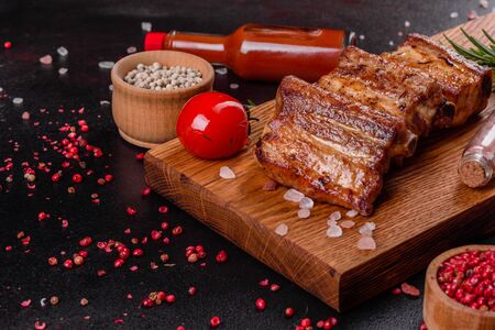 Fried ribs with rosemary, onion, sauce on a concrete background. Dark table. Place for text, copyspaceの写真素材