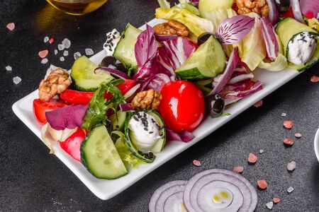 Greek salad with fresh vegetables, feta cheese and black olives. Healthy salad with cherry tomatoes, organic olives, cucumber, lettuce and spicesの写真素材