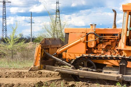 Industrial building construction site bulldozer leveling and moving soil during highway building. Yellow bulldozer at a loamy construction siteの写真素材