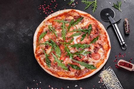 Fresh pizza baked in oven with arugula, salami, cherry tomatoes and mozzarella. Italian cuisineの写真素材