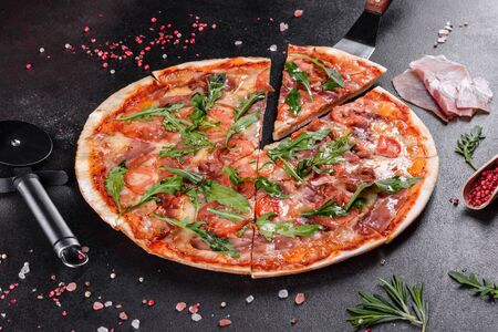 Fresh pizza baked in oven with arugula, salami, cherry tomatoes and mozzarella. Italian cuisineの写真素材