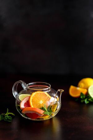 Hot fruit tea with lemon, mint, orange, lime and grapefruit in a beautiful glass teapotの写真素材